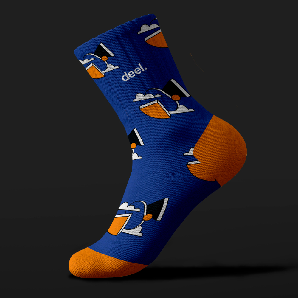 Full service 24 Blue sock with an orange heel and toe, featuring a cartoon graphic of a person with a hat and sunglasses against a dark background. The word deel. is printed near the top, showcasing unlimited graphic design creativity.